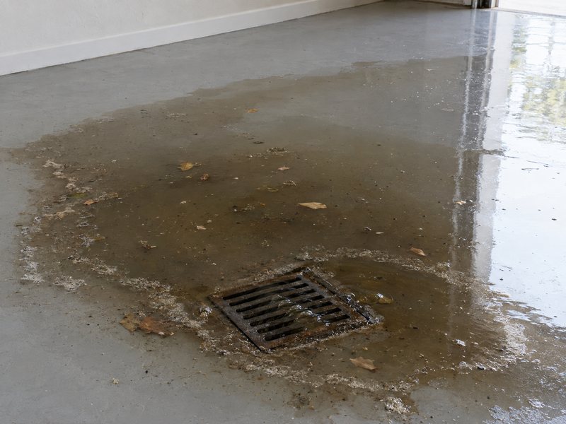 Dirty water and leaves backing up through a square garage floor drain