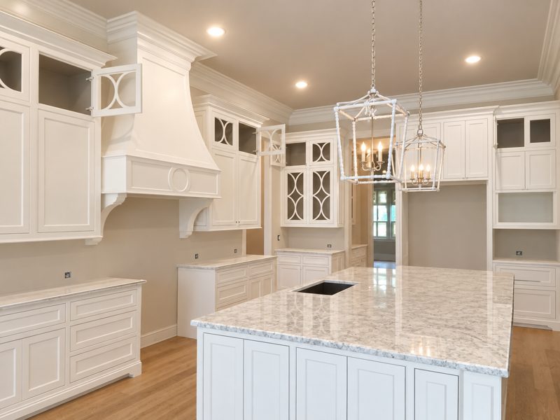 Finished white kitchen with marble island and pendant lights
