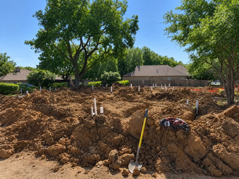 Excavated lot with underground plumbing stubs staked out