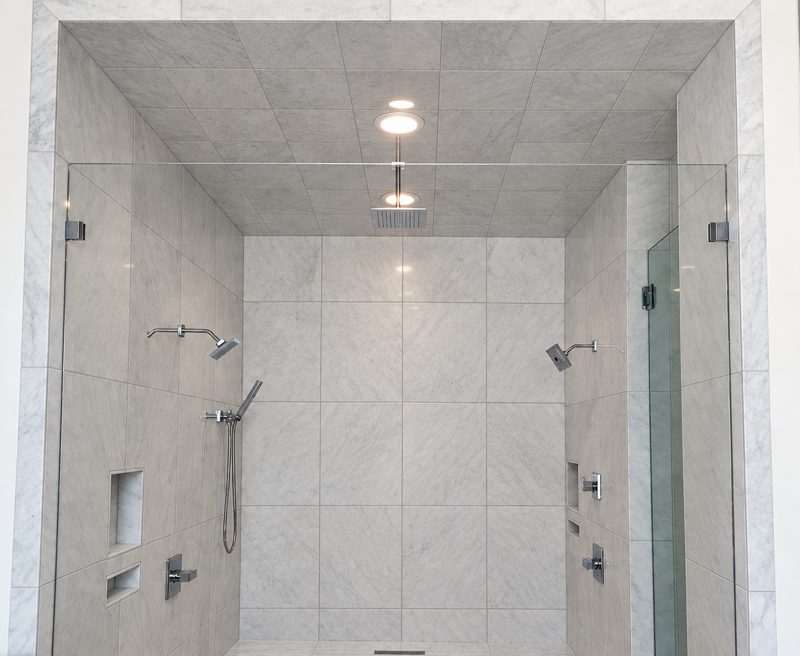 Tiled walk-in shower with two shower heads and a hand shower